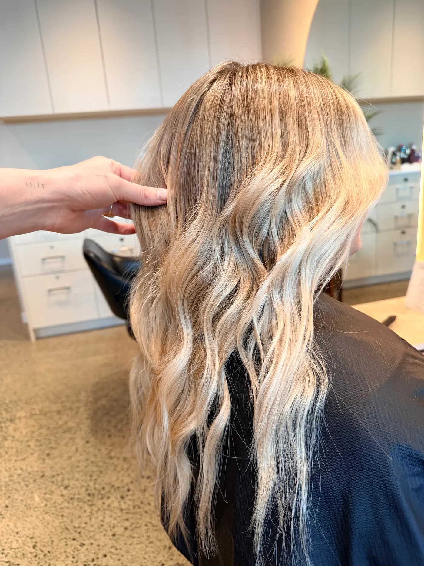 Lived-in blonde with soft dimension through the lengths, held up in the chair