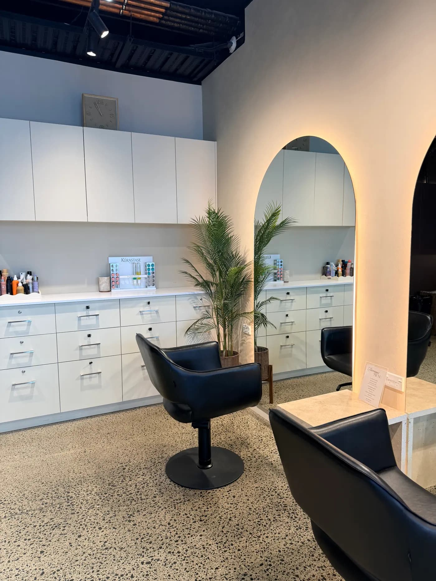 The salon floor at Jenna Ellen Hair: white cabinetry, the Kérastase display and an arched, back-lit mirror